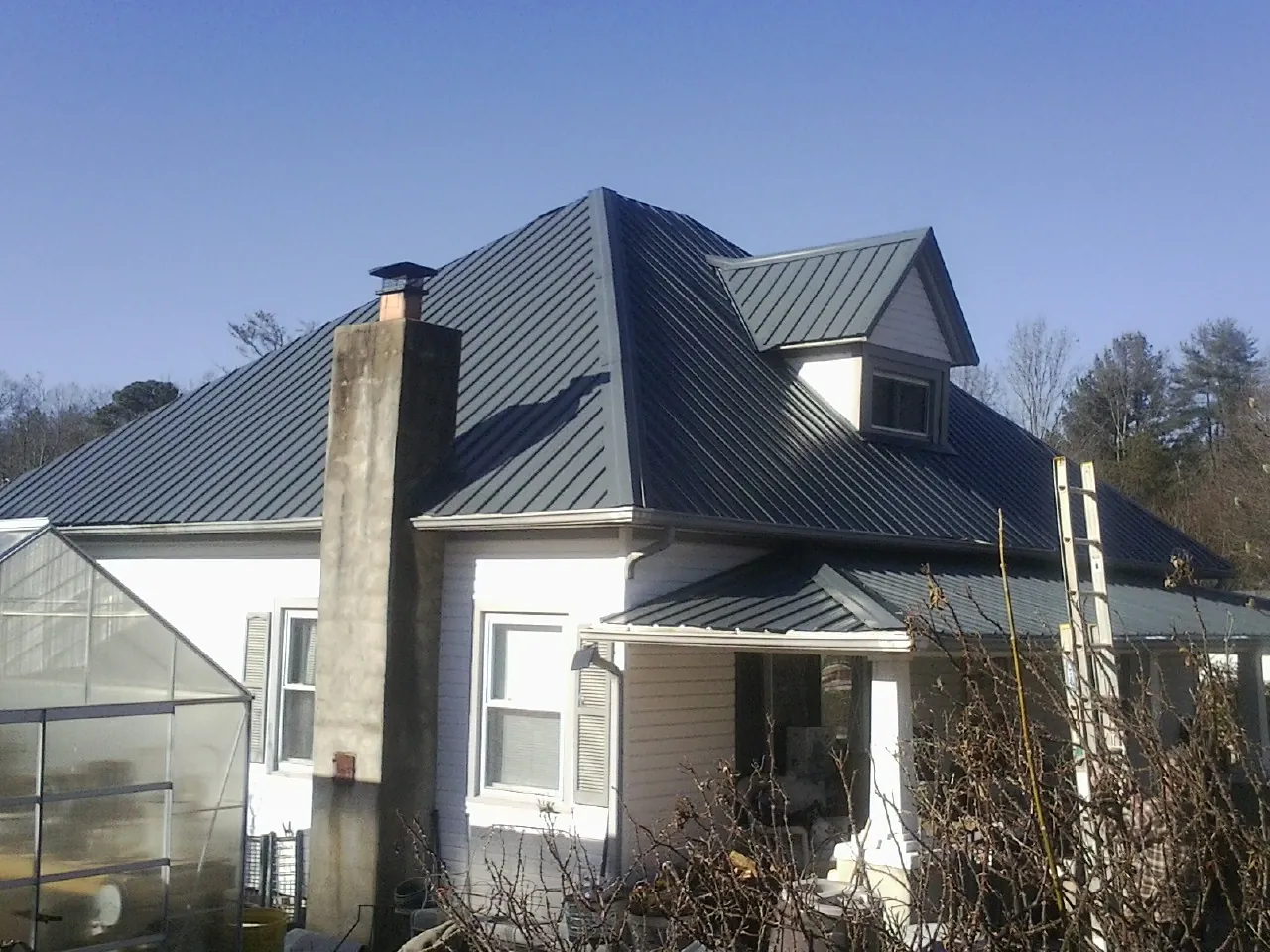 Dark blue standing seam metal roof on a white farmhouse with dormer — Slate & Tile Roof Repair by Roofing Brothers in Dahlonega