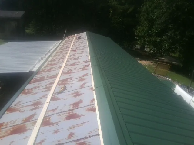 Old rusted panels beside newly installed green metal roofing — Wind Damage Roof Repair by Roofing Brothers in Dahlonega