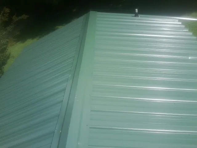 New green metal panels meeting at the ridge of a roof — Flat Roof Repair work by our crew in Dahlonega