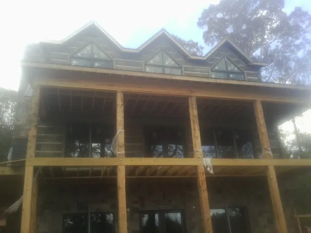 Dormers and porch framing on a large log home under construction — Roof Coating work by our crew in Dahlonega