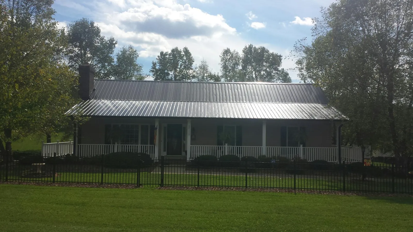 Gray metal roof on a brick ranch with a full width front porch — Gutter Guard Installation work by our crew in Dahlonega
