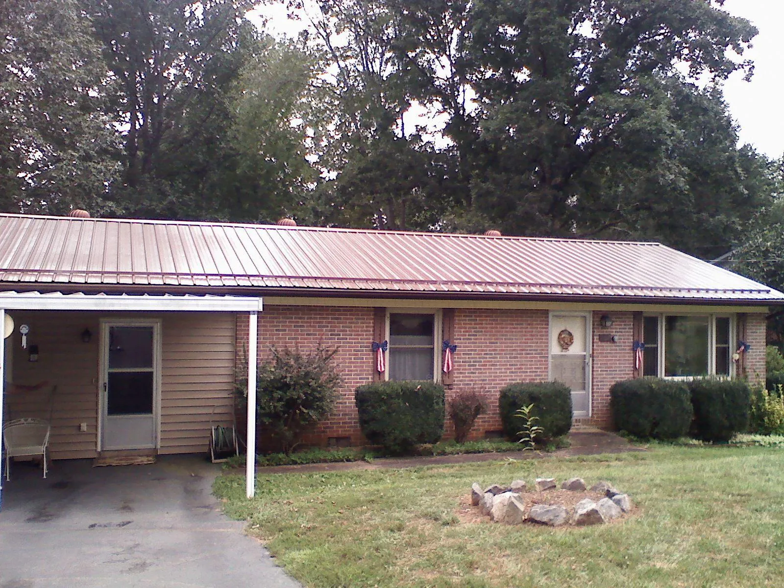 Bronze metal roof and carport on a brick ranch home — Roof Repair work by our crew in Dahlonega