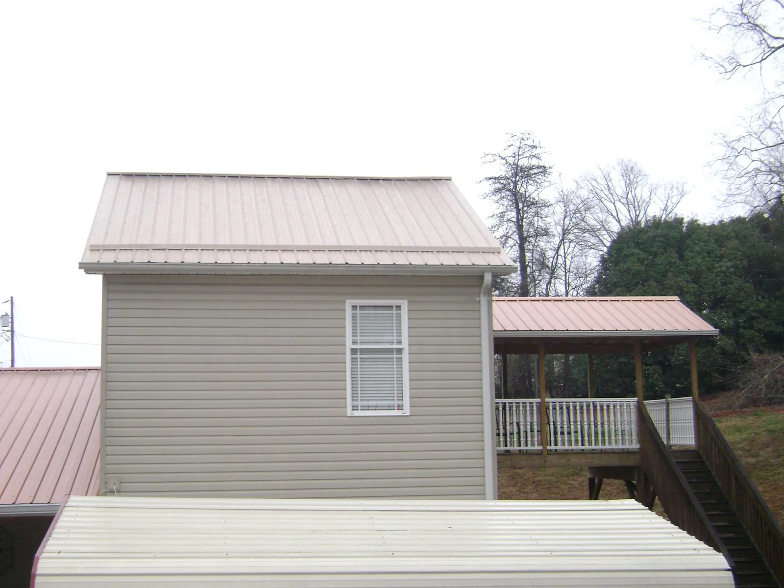 Tan metal roofs on a two story addition and attached porch, from a Roof Replacement job in Dahlonega