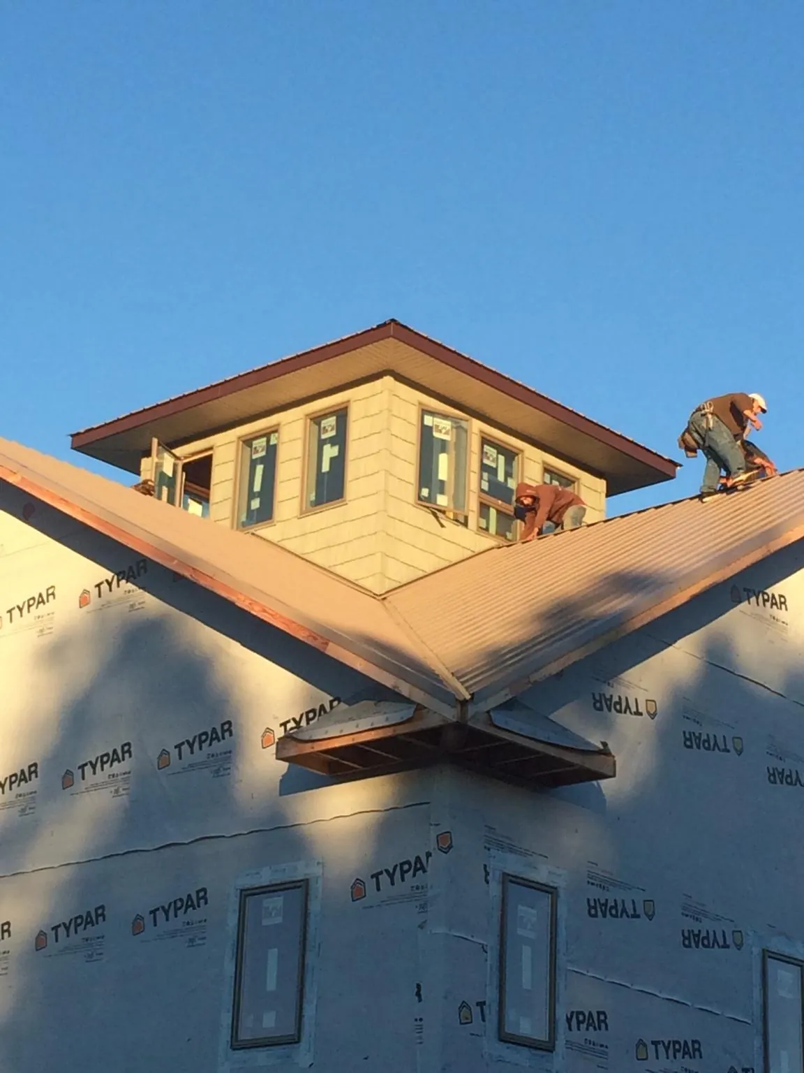 Roofers working around a rooftop cupola on a new metal roof at sunset — Roof Waterproofing in Dahlonega by Roofing Brothers